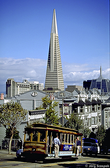 Ein die California Street hinunterfahrender Cable Car mit der Transamerica Pyramide im Hintergrund